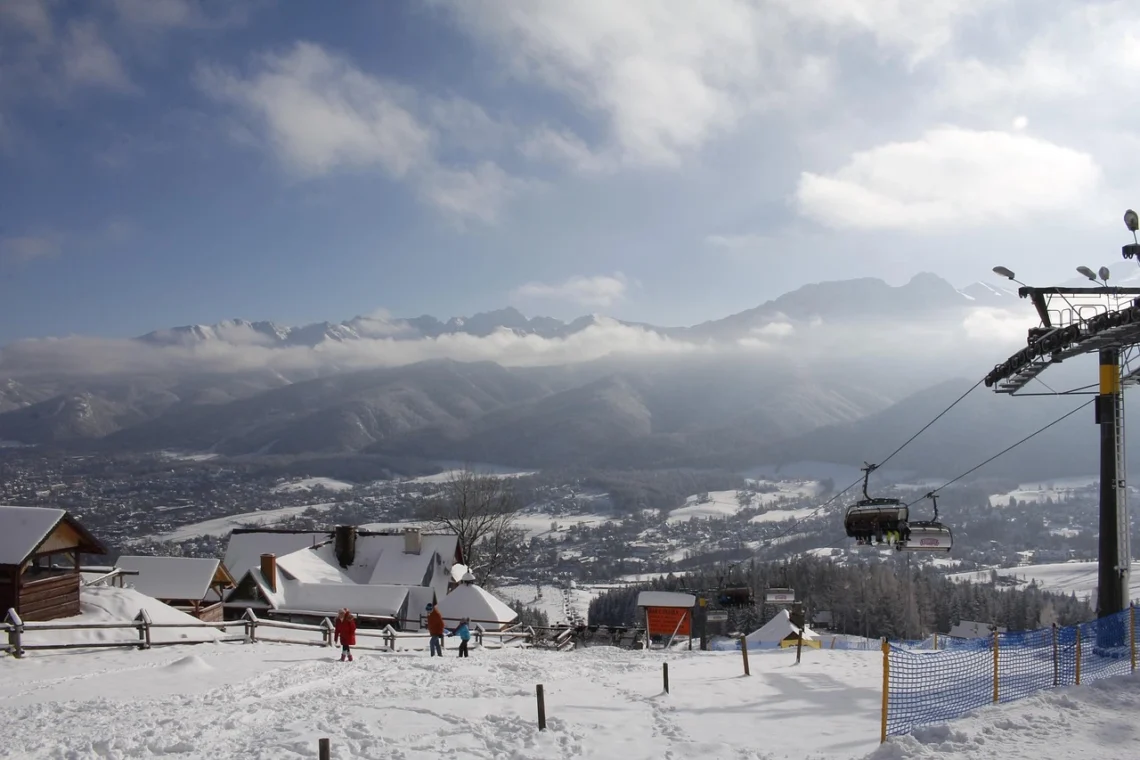 Blick auf die Stadt Zakopane im Winter. Im Vordergrund ist das Skigebiet der Stadt mit Schnee bedeckt, im Hintergrund das Tal, in dem Zakopane liegt.